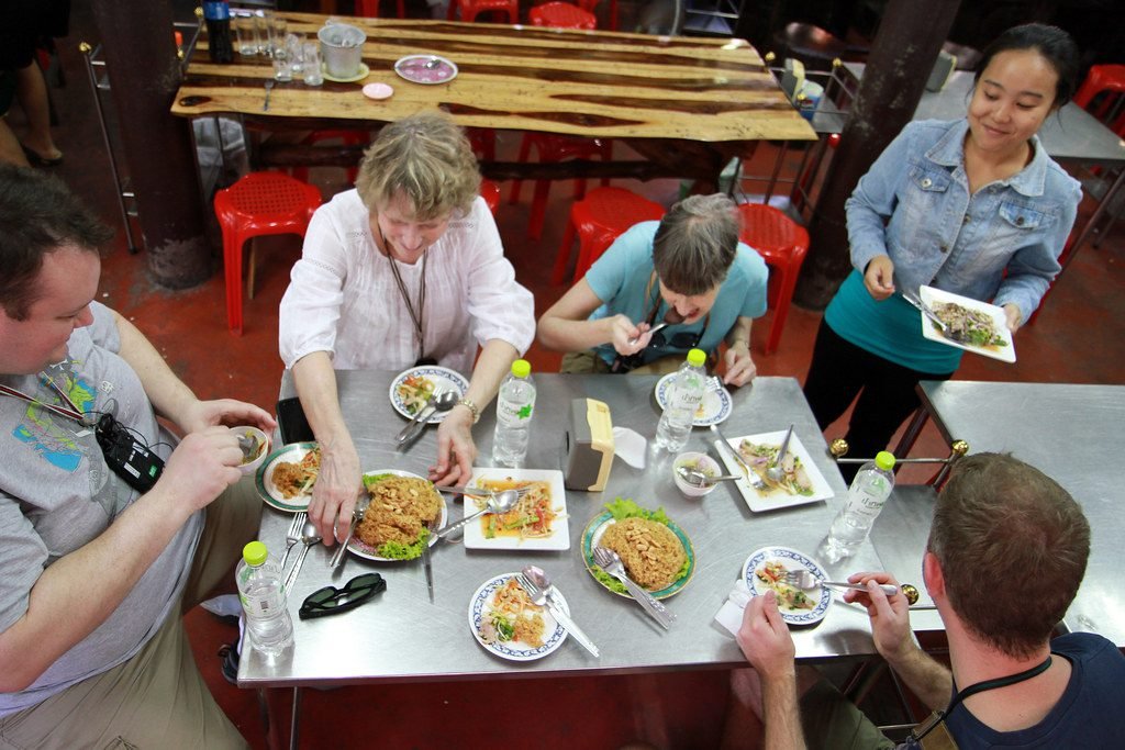 Thai food tour guide explaining exotic ingredients to tourists at Bangkok fresh market