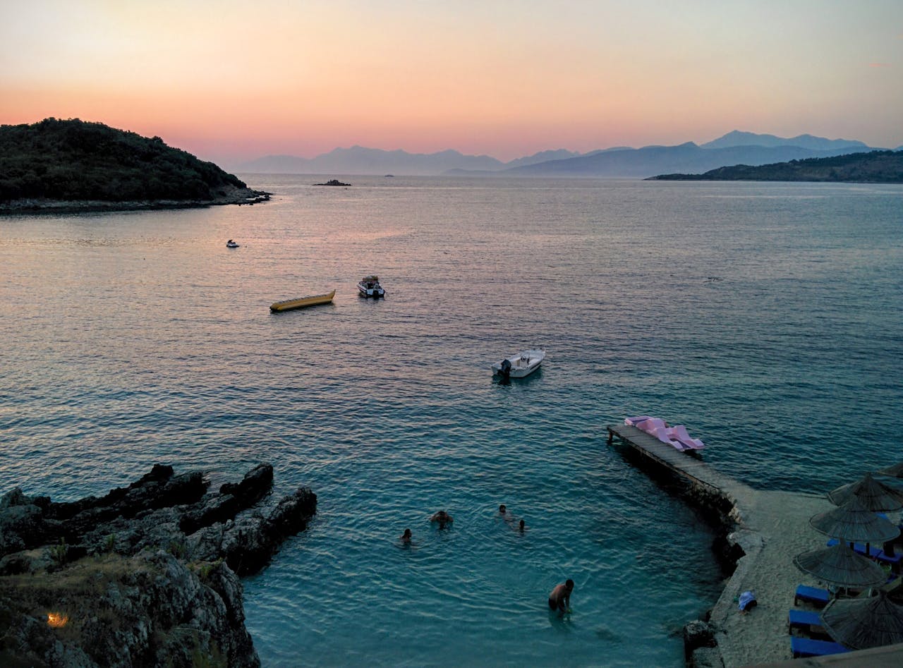 People Swimming in the Sea Near Mountain Rocks, Albania