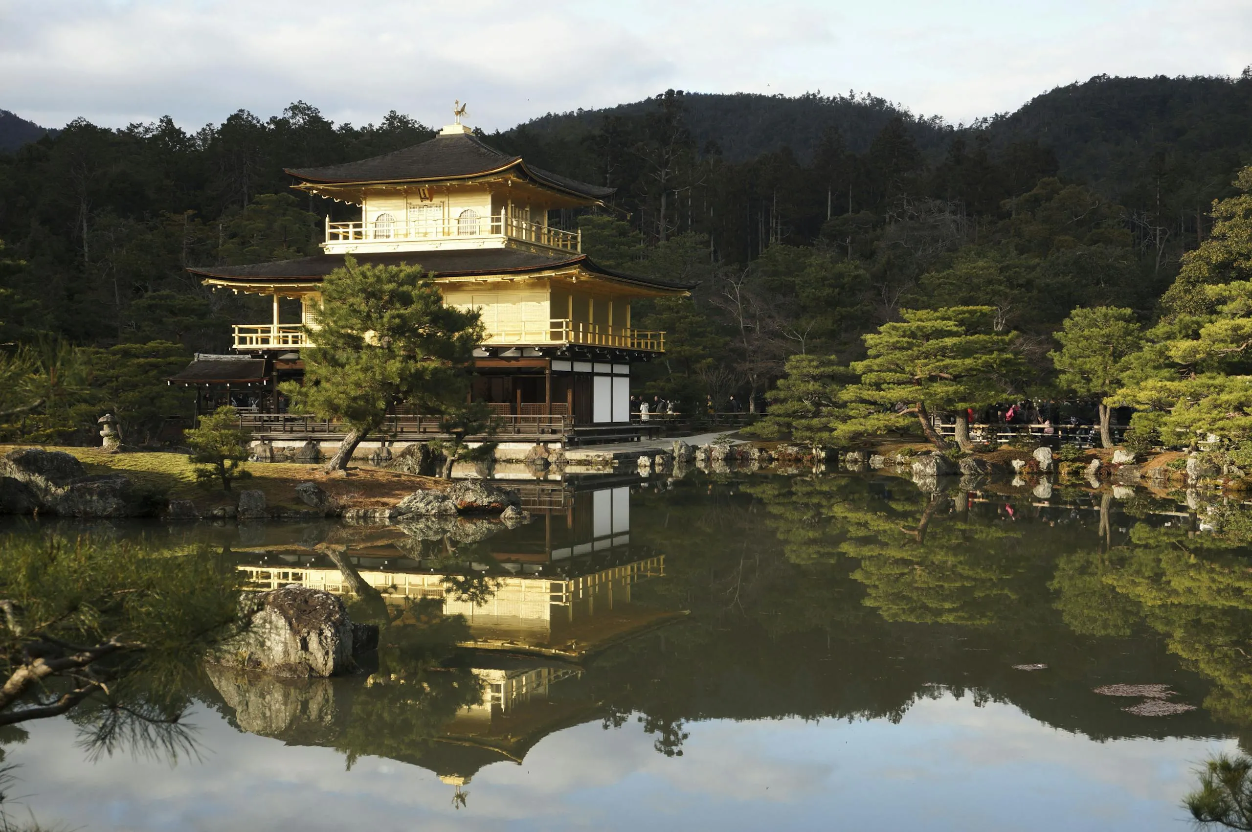 Serene view of Kinkaku-ji Temple in Kyoto with a calm reflection in surrounding pond.