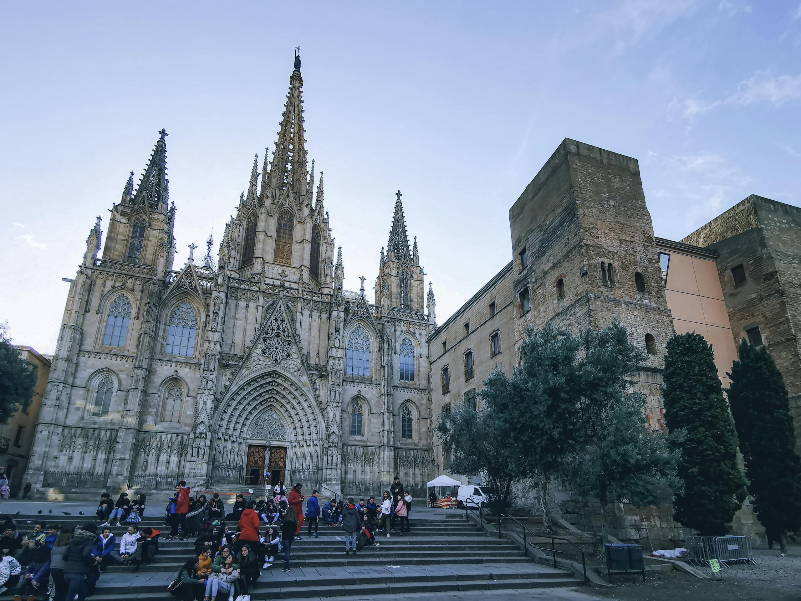 Stunning gothic cathedral facade in Barcelona with people on steps during daytime.