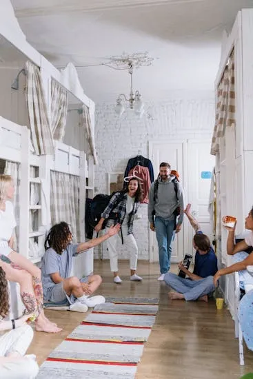 A group of diverse, cheerful backpackers socializing in a cozy dorm room, creating a lively atmosphere.