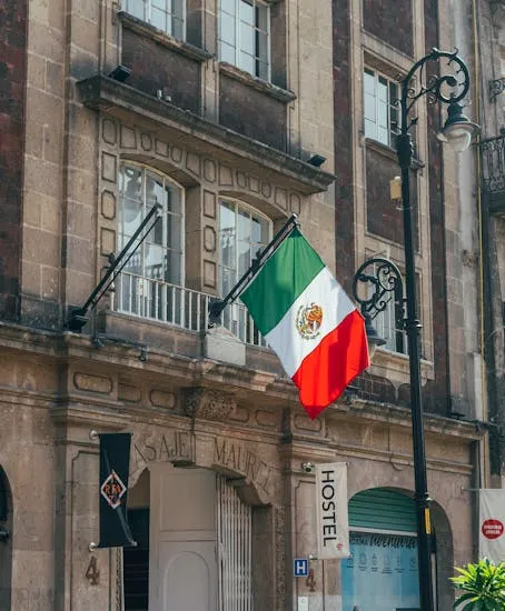 A Mexican flag adorns a historic building in Ciudad de México, showcasing cultural pride.