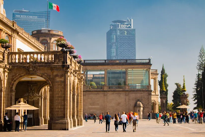 Chapultepec Castle in urban Mexico City with flag and skyline view.