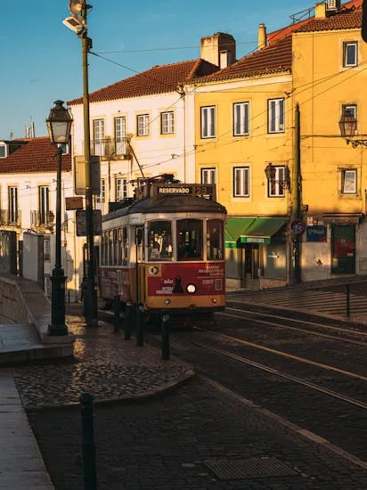 Charming tram navigating through the historic city streets of Lisbon during a sunny day.