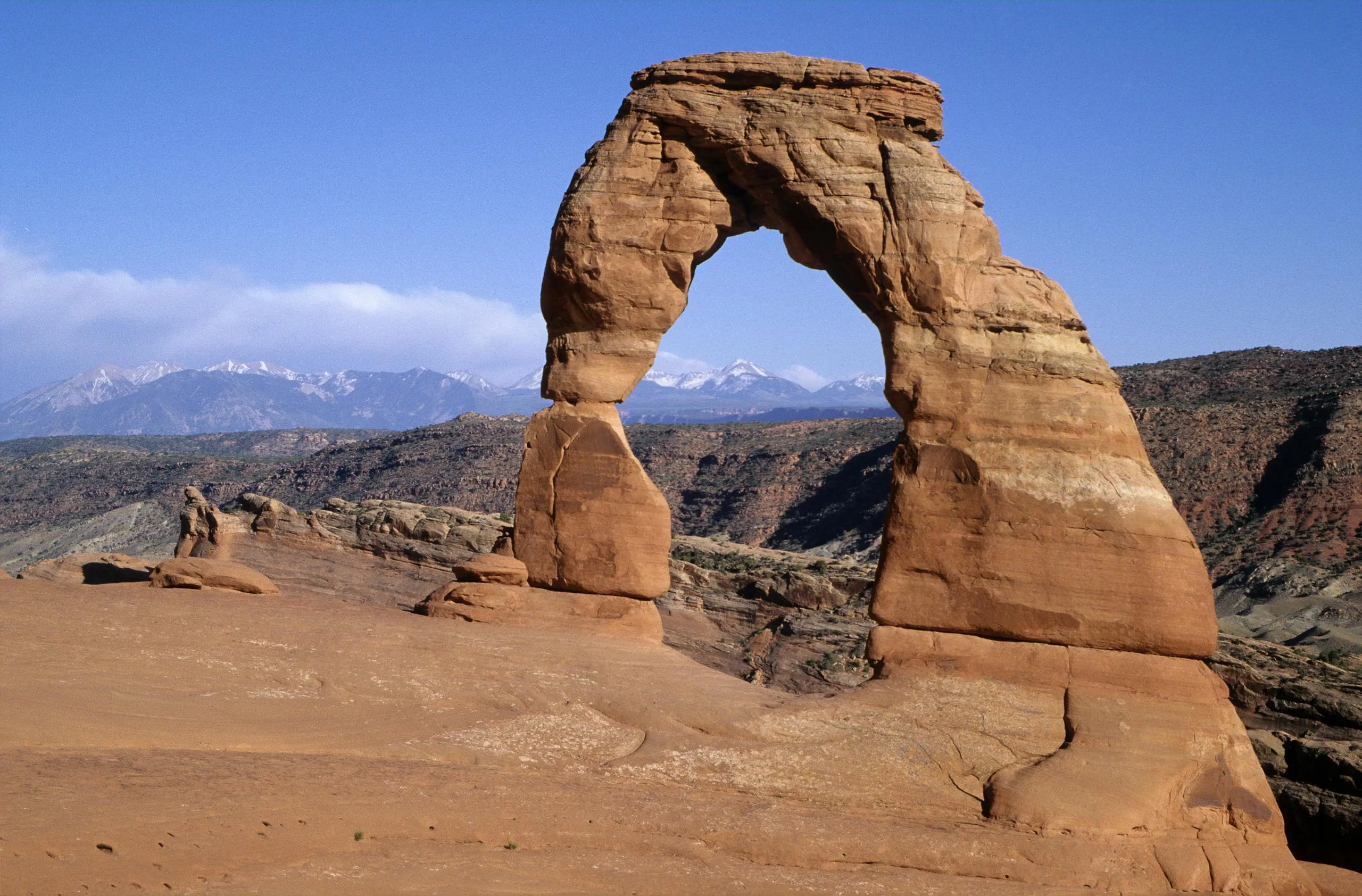 Iconic Delicate Arch against a stunning mountainous backdrop in Moab, Utah.