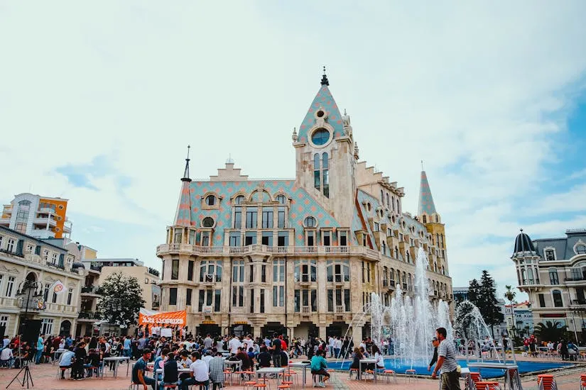 People enjoying a lively day at Europe Square, Batumi, with a stunning architectural backdrop and fountain display.