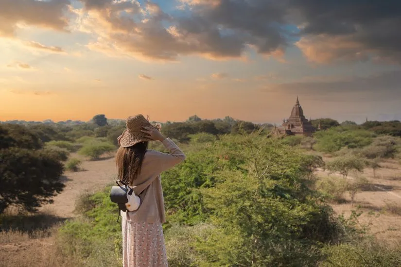 Woman in crochet hat exploring Bagan temple landscape at sunset, Myanmar.