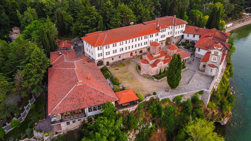 Aerial view of historic Saint Naum Monastery by Lake Ohrid, surrounded by lush greenery.