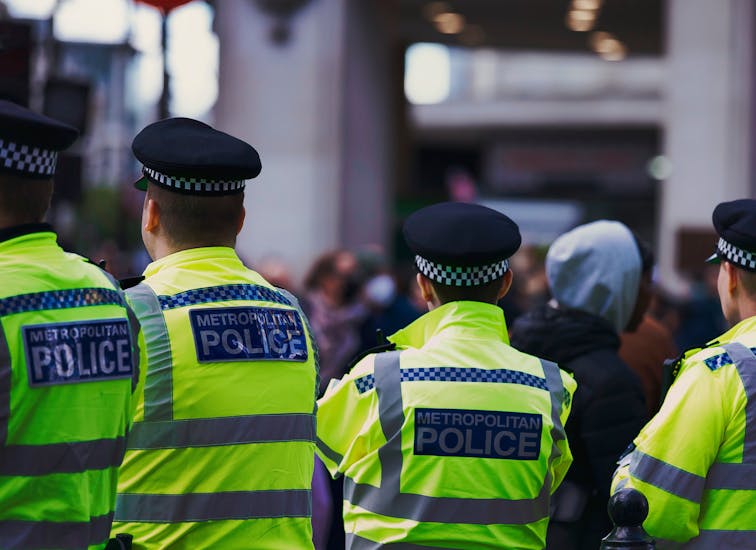 Metropolitan Police officers in high-visibility jackets on patrol in London.